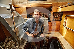 Bearded young man repairing boat engine and looking at camera