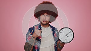 Bearded young man showing time on clock watch, ok, thumb up, approve, pointing finger at camera