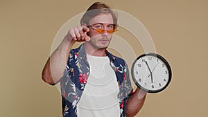 Bearded young man showing time on clock watch, ok, thumb up, approve, pointing finger at camera