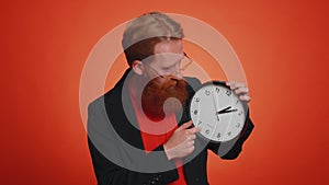 Bearded young man showing time on clock watch, ok, thumb up, approve, pointing finger at camera