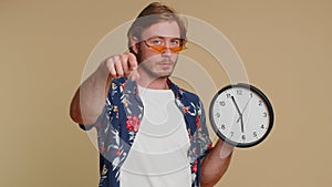 Bearded young man showing time on clock watch, ok, thumb up, approve, pointing finger at camera