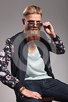 Bearded young man takes off sunglasses