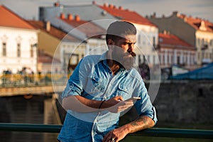 Bearded young man texting on the cell phone.