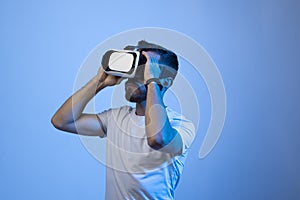 Bearded young man using VR glasses, touching with a hand copy space free space, playing virtual video games with friends