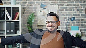 Bearded young man working with laptop then stretching arms relaxing in office