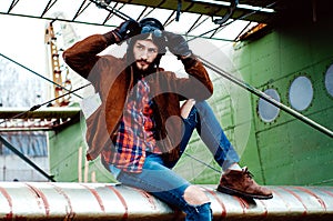 Bearded young pilot sits on the wing of an old plane