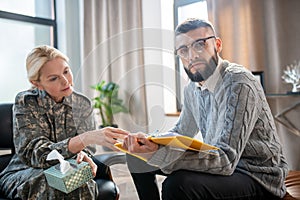 Bearded young psychoanalyst helping servicewoman with anxiety