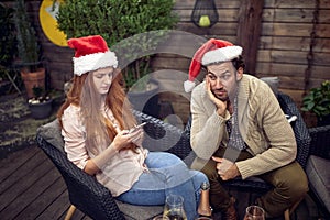Beardy guy in company of boring female typing on her cell phone on new year party