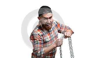 Beared man in cap and checked shirt emotionally trying to break the iron chain on white background