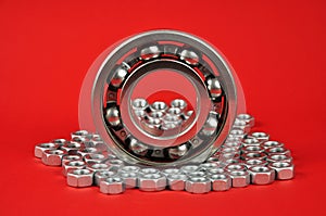 Bearing and metal nuts on a red background.