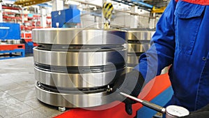 Bearing producing factory. Worker controlling technical characteristics of ready items. Machinery and industry concept