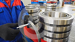 Bearing producing factory. Worker controlling technical characteristics of ready items. Machinery and industry concept