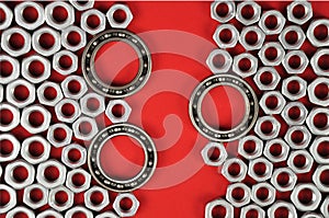 Bearings and metal nuts on a red background.