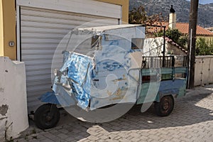 Beat-up old three-wheel truck in back lane in Greece