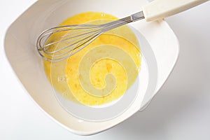 Beaten egg yolks in a bowl with whisk