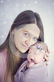 Beatific beautiful mother with long hair with beloved newborn daughter in hands
