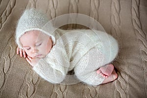 Beatiful baby boy in white knitted cloths and hat, sleeping