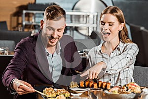 Beatiful happy woman pointing at something while couple having dinner