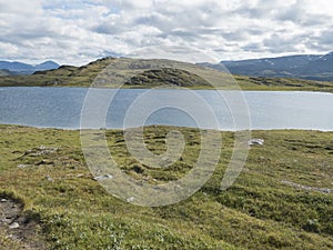 Beatiful northern landscape, tundra in Swedish Lapland with blue artic lake, green hills and mountains at
