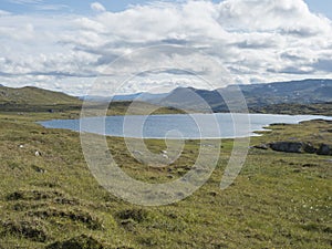 Beatiful northern landscape, tundra in Swedish Lapland with blue artic lake, green hills and mountains at