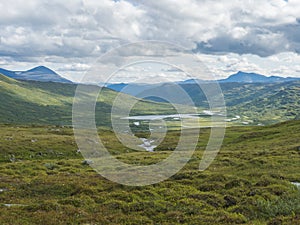 Beatiful northern landscape, tundra in Swedish Lapland with blue artic river and lake, green hills and mountains at