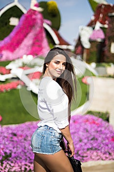 Beatiful young girl standing and enjoy flowers in Dubai Miracle Garden