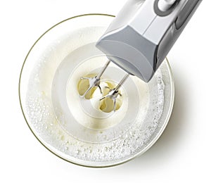 Beating egg whites cream with mixer in the bowl