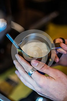 Beating of milk in milk seller at the espresso steamer