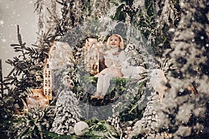 beauatiful little girl relaxes with a christmas decoration with trees and a little white rabbit