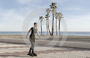 Beauful fit woman roller skating in promenade at the seaside with palm trees on background.Sport and fitness lifestyle concept