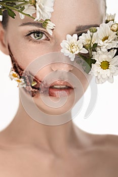 Beauiful girl with huge wound on cheek and flowers covering face
