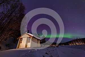 Beauitful aurora over the night sky, wooden house