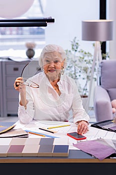 Beauteous aging executive comely sitting at deluged with papers table