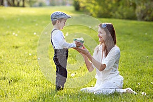 Beautful kid and mom in spring park, flower and present