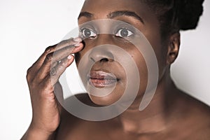 Beautful young African woman feeling the skin around her eyes