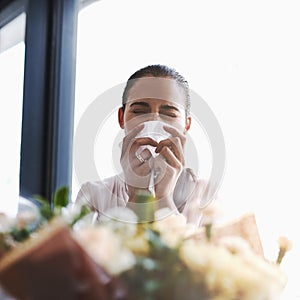 These are beauti...achoo. a young businesswoman blowing her nose in front of a bouquet of flowers. photo