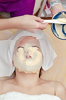 Beautician applies alginate mask on woman patient face