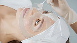 Beautician applies cleansing mask face with a brush.