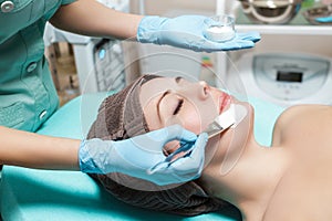 Beautician applies face mask on beautiful young woman in Spa salon. cosmetic procedure skin care. Microdermabrasion