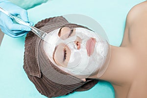 Beautician applies face mask on beautiful young woman in Spa salon. cosmetic procedure skin care. Microdermabrasion