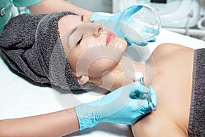 Beautician applies face mask with brush to beautiful young woman in Spa salon. cosmetic procedure skin care.