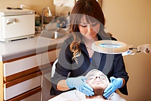 Beautician Applying Cream To Male Client In Clinic