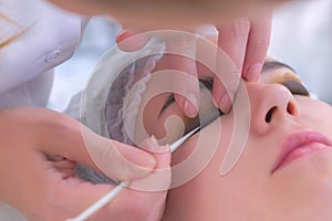 Beautician applying curler on girl`s eyelid for eyelash lifting and laminating.