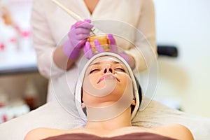 Beautician applying facial mask to woman at spa