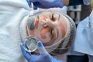 Beautician applying facial mask using brush. Beauty treatment in spa salon