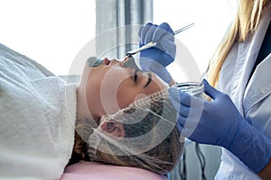 Beautician applying facial mask using brush. Beauty treatment in spa salon