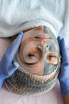 Beautician applying facial mask using brush. Beauty treatment in spa salon