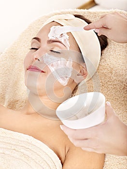 Beautician applying facial mask by woman. photo