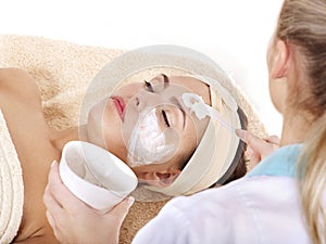 Beautician applying facial mask by woman.