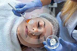 Beautician applying healing cream on a young female face client